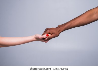 White Caucasian Female Hand And Black African American Male Hand Holding Fingers Together In World Unity And Racial Love And Understanding In Tolerance.