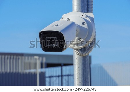 White CCTV camera on the street, security in the city. Covert recording of what is happening. Modern technology and equipment.