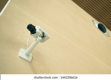 White CCTV Camera On The Yellow Wall At The Airport. The Security Of A Hidden Camera Video Surveillance Indoors.