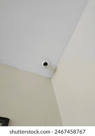 A white CCTV camera positioned in the corner of the room, ensuring surveillance and security with its discreet presence.