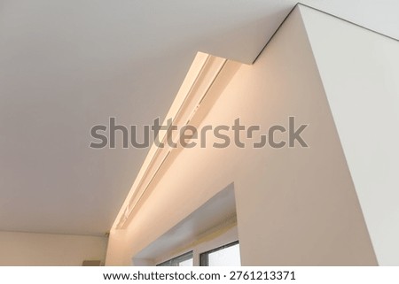 A white ceiling with a built-in thin light strip. Hidden LED lighting creates a 
