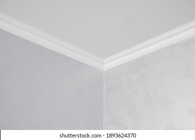 White ceiling with a white plinth in a room with gray painted walls. Decoration of the corner between the ceiling and the wall in the room. Ceiling molding in the interior. Detail of corner. - Shutterstock ID 1893624370