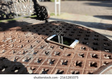 White Cell Phone With Reflection Screen On Metal Table