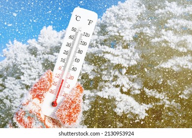 White celsius and fahrenheit scale thermometer in hand. Ambient temperature minus 10 degrees celsius
