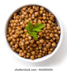 White Ceramic Bowl Of Brown Cooked Lentils With Parsley Isolated On White From Above.