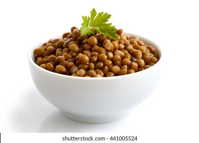 White Ceramic Bowl Of Brown Cooked Lentils With Parsley Isolated On White In Perspective.