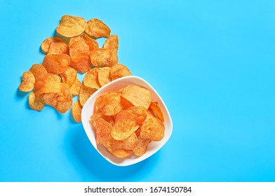 White Ceramic Bowl Full Of Potato Chips On Blue Background. Space For Text. Top View