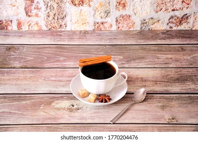 White ceramic cup of black coffee on a saucer with a spoon decorated with anise and cinnamon sticks. Close-up. - Powered by Shutterstock