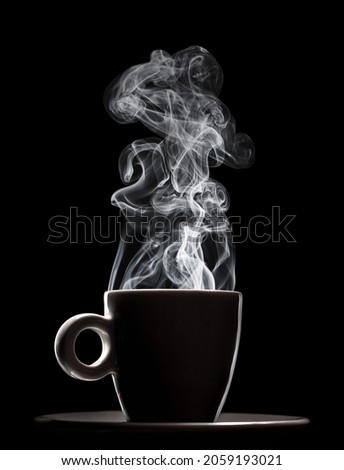 White ceramic cup of fresh steaming fragrant aromatic morning hot coffee over black background. Smoke from hot coffee.