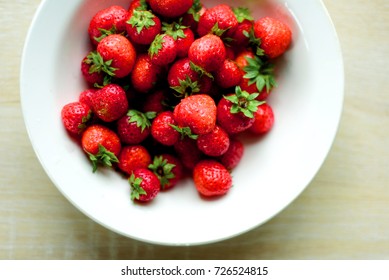 White Ceramic Kitchen Bowl Full Of Red Strawberries Taken From An Aerial Overhead Position With Domestic Counter Background.