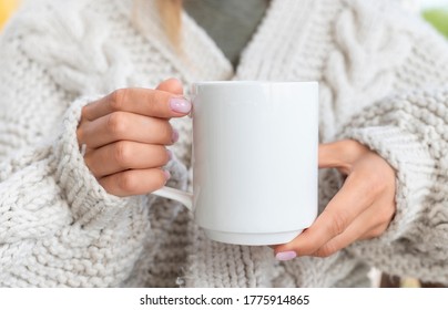 White Ceramic Mug Mockup. Woman In Sweater Holding A Warm Cup Of Coffee. Copy Space For Your Print