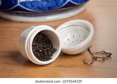 White ceramic open tea strainer with dried Chinese Kee Mun tea leaves close up to start making tea 