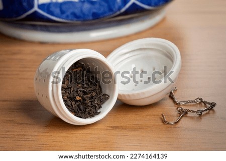 White ceramic open tea strainer with dried Chinese Kee Mun tea leaves close up to start making tea 