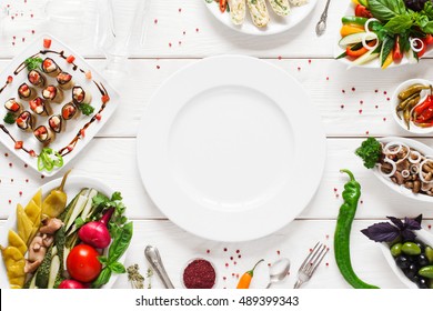 White ceramic plate surrounded by snacks, void. Variety of vegetarian meals make frame for empty dish. Cuisine, menu, food concept - Powered by Shutterstock