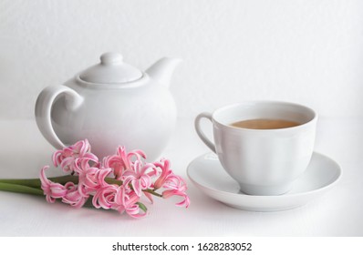 White ceramic teapot and cup with tea. Hyacinth flower on a white background. Selective focus. Breakfast concept. Close up.