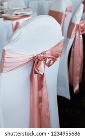 White Chair Cover With Pink Satin Silk Sash Tied In A Bow At Wedding Reception