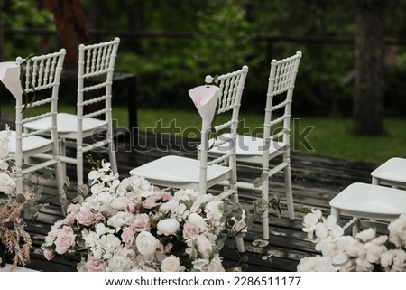 White chairs with white and pink flowers decoration in the park for wedding ceremony.	