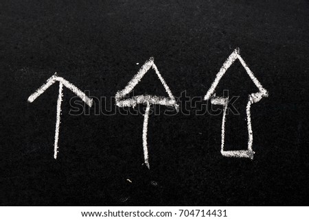 White chalk drawing as arrow shape on black board background
