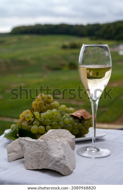 White\
chalk stones from Cote des Blancs near Epernay, region Champagne,\
France, glass of blanc de blancs champagne from grand cru vineyards\
in Cramant and white chardonnay grapes close\
up