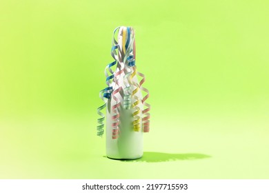 White Champagne Bottle With Color Paper Curls  On Green Background. Party Concept.