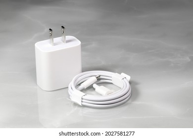 White charger adapter and white USB cable on a white background, New Charger and cable connector for gadgets isolated on a white background. The concept of charging technology to mobile phones. 