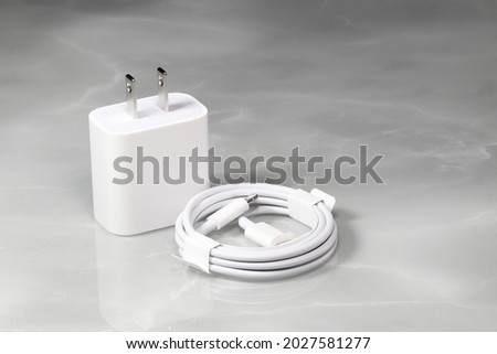 White charger adapter and white USB cable on a white background, New Charger and cable connector for gadgets isolated on a white background. The concept of charging technology to mobile phones. 