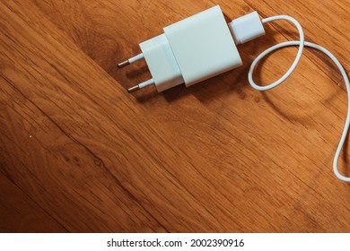 White charger with cable on a wooden background.
				