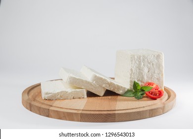 White Cheese With Some Garnitures Such As Lettuce, Cherry Tomato Slice And Basil On A Wooden Plate, White Background