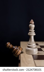 The white chess king discards the opponent's black pawn from the chessboard. Vertical photo. The concept of defeating the opponent, the victory of white pieces in a chess game.