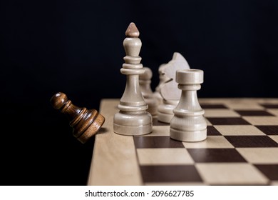 The white chess king and his team consisting of a rook, knight and pawn discards the opponent's black pawn from the chessboard. Concept of White's victory in chess, victory over the opponent, teamwork