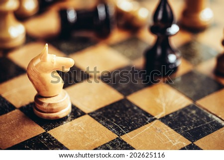 White chess knight and black bishop figures standing on chessboard