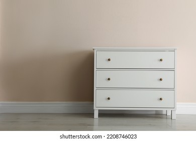 White chest of drawers near beige wall. Space for text - Shutterstock ID 2208746023