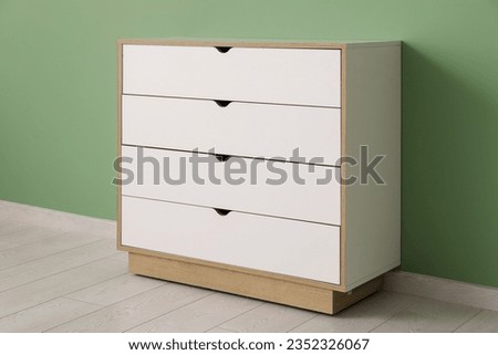 White chest of drawers near green wall in room, closeup