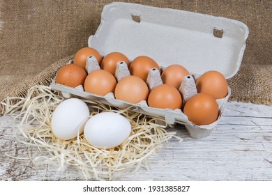 White Chicken Eggs On A Wood Shavings And Brown Eggs In Carton Made Of Recycled Paper Pulp On An Old Wooden Surface With Sackcloth, Close-up  
