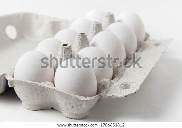 白い鶏の卵を開いた紙の箱に入れたもの