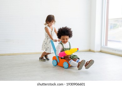 
A White Child And A Black Child Playing A Stroller, Black Looks, Smiling At The Camera. Concept Non-racism
