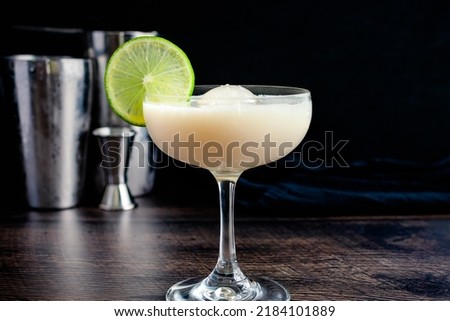 White Chocolate Gimlet Gin Cocktail with Ice Sphere: Cocktail made with gin, lime cordial, and white chocolate liqueur in a coupe glass