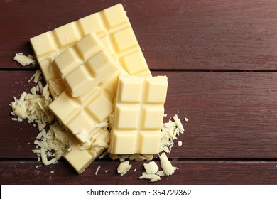 White Chocolate Pieces On Color Wooden Background