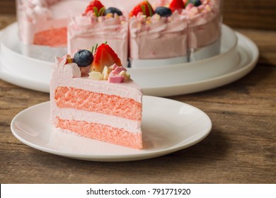 White chocolate strawberry yogurt cake decorated with fresh fruits and chocolate chunk on wood table. Delicious and sweet pink strawberry cake for Valentines or birthday party. Homemade bakery concept