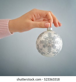 White christmas ball in female hand on blue background