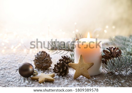 White Christmas candle on rustic wooden boards - Decoration with natural elements, twigs, pine cones and cookies.
