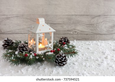 White Christmas lantern with lit candle on fir tree twigs decorated with holly berries, pine cones and snowflakes.  - Powered by Shutterstock