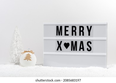 White Christmas tree, Christmas bauble and lightbox with text MERRY XMAS on a table with snow. Minimal Christmas or New Year concept. - Powered by Shutterstock