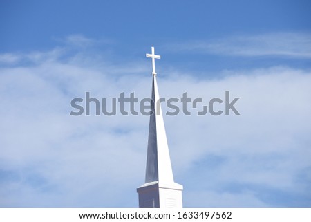 A white church steeple on a blue sky with white clounds 