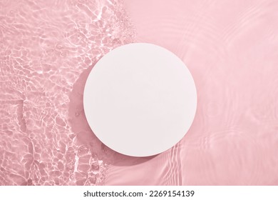 White circular empty podium, set on a pink background with water and tiny ripples. Blank for cosmetics presentation. Top view, flat lay cosmetic mockup. Stock Photo