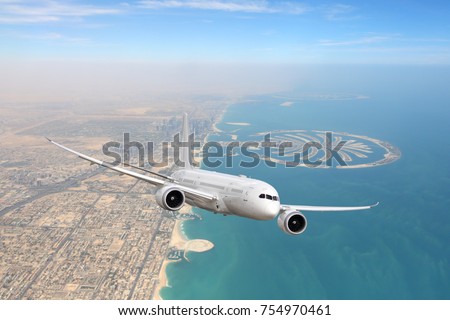 White civil twin-engine passenger airliner flying above Dubai city and coastline.