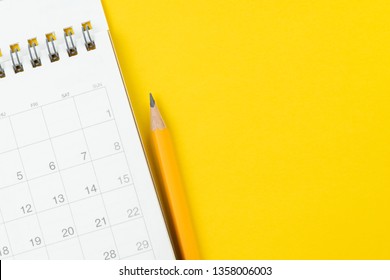 White Clean Calendar With Yellow Pencil On Solid Yellow Background With Copy Space Using As Reminder, Schedule Or Business Project Plan And Timeline Concept.