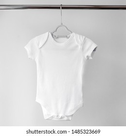 White clean clothes for a newborn on a hanger. Copy space. The concept of clothes, motherhood, fashion and newborn.
