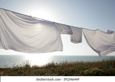 White clean sheets outdoors. Drying on a rope on background of beautiful scenery in the sun