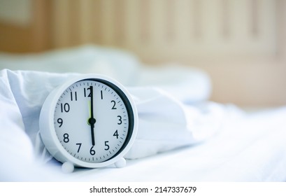 The white clock shows 6:00 AM, waking you up from bed. The concept of time and rest. Wake up plug.
